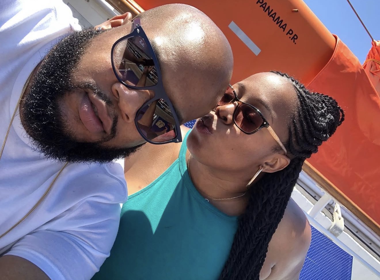A kiss on the ship deck beside an orange lifeboat